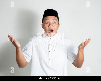 Portrait de l'homme asiatique musulman montre une expression choquée et surprise en ouvrant sa main Banque D'Images