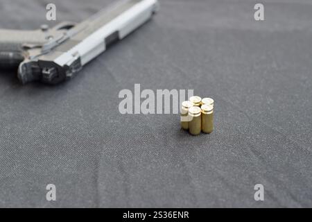 balles de 9 mm et pistolet sur un tissu noir. Un ensemble d'éléments de plage de prise de vue ou un kit d'autodéfense. Golden Shells près du pistolet Banque D'Images