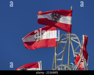 Plusieurs drapeaux autrichiens aux armoiries nationales flottent dans le vent. Autriche contre un ciel bleu Banque D'Images