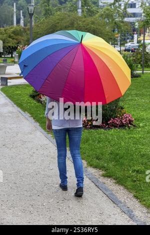 Une jeune femme marche sous la pluie avec un parapluie coloré à la main. Autriche Banque D'Images