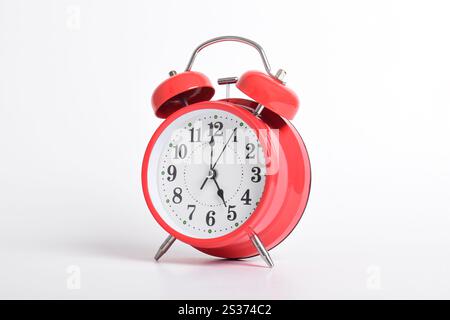 Réveil rouge réglé à cinq heures isolé sur fond blanc. Gros plan avec masque Banque D'Images
