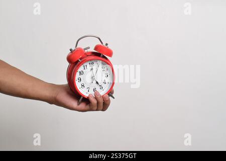 Réveil rouge vintage à la main. Réveil rouge rond isolé sur fond blanc montre 5 heures du matin Banque D'Images