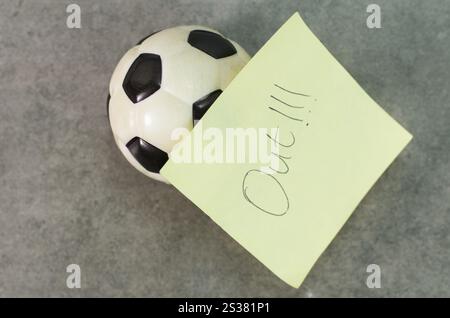 Objet de ballon de football avec note d'avertissement sportif sur des notes adhésives jaunes Banque D'Images
