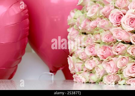 Bouquet de roses colorées et de ballons rouges en forme de coeur en gros plan. Fleurs roses plein cadre. Bouquet de roses colorées et ballons rouges en forme de Banque D'Images