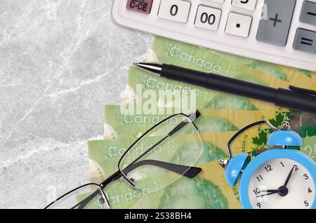 Billets de 20 dollars canadiens et calculatrice avec lunettes et stylo. Concept de prêt commercial ou de saison de paiement d'impôt. Planification financière et temps pour payer les impôts. Banque D'Images