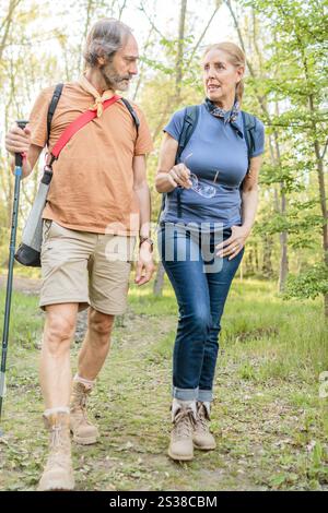 Couple senior marchant à travers la forêt à madrid, espagne, appréciant la nature et parlant pendant la randonnée Banque D'Images