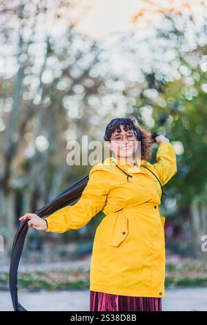 Femme portant un imperméable jaune profitant de la journée d'automne dans le parc Banque D'Images