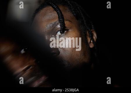 Gros plan de l'homme afro-américain regardant avec un œil et un appareil photo cachant la moitié du visage dans l'obscurité, effet de double exposition, espace de copie Banque D'Images