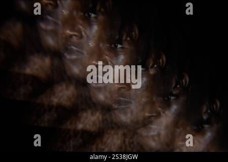 Image abstraite avec effet d'exposition multiple de l'homme afro-américain regardant loin avec expression tristement sur le visage dans la lumière basse, espace de copie Banque D'Images