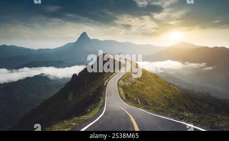 Une route pittoresque serpente jusqu'à une colline escarpée, menant à une montagne majestueuse debout en arrière-plan. La route disparaît dans la distance Banque D'Images