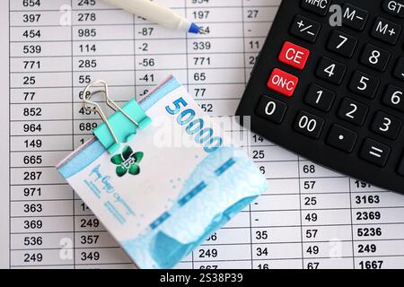 Calculs d'affaires avec des factures d'argent rupiah indonésiennes et calculatrice avec stylo sur la table de bureau de gros plan. Le concept d'entreprise et d'impôt Banque D'Images