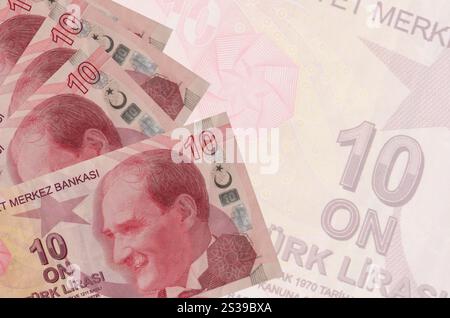 10 billets de lires turques se trouve en pile sur fond de gros billet de banque semi-transparent. Fond d'entreprise abstrait avec espace de copie. 10 livres turques Banque D'Images