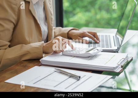 Femme d'affaires calculant l'état financier sur la calculatrice de déclaration d'impôt en ligne et de paiement Banque D'Images