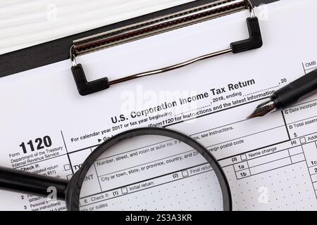 IRS Form 1120 US Corporation Income Tax Return Blank sur tablette A4 repose sur la table de bureau avec stylo et loupe gros plan. Formulaire IRS 1120 US Banque D'Images