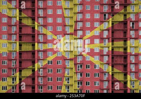 Drapeau macédonien représenté en couleurs de peinture sur un bâtiment résidentiel à plusieurs étages en construction. Bannière texturée sur fond de grand mur de briques. Banque D'Images