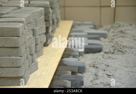 Rangées de dalles de passerelle grise et gris foncé situées à l'extérieur. Matériau pour dalles de pavage par mosaïque en cours. Procédé d'installation de pavés. Lignes de Banque D'Images