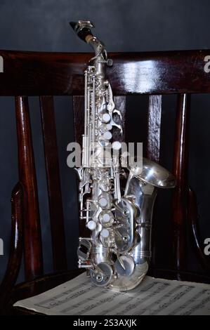 Un saxophone argenté sur une vieille chaise Banque D'Images