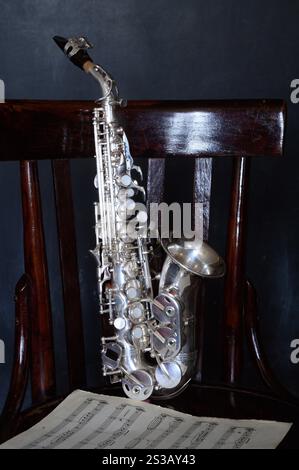 Un saxophone argenté sur une vieille chaise Banque D'Images
