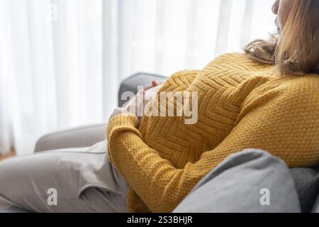 Femme enceinte tient les mains sur le ventre touchant son bébé se souciant de sa santé belle femme enceinte heureuse photo d'humeur tendre de la grossesse. Banque D'Images