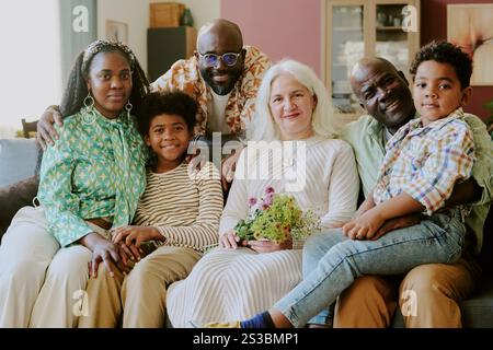 Portrait moyen en gros plan d'une famille biraciale souriante et serrée tout en posant pour la photo Banque D'Images