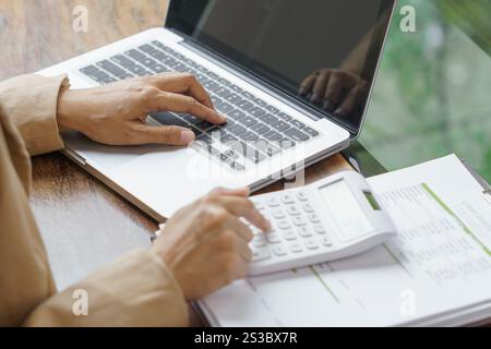 Femme d'affaires calculant l'état financier sur la calculatrice de déclaration d'impôt en ligne et de paiement Banque D'Images