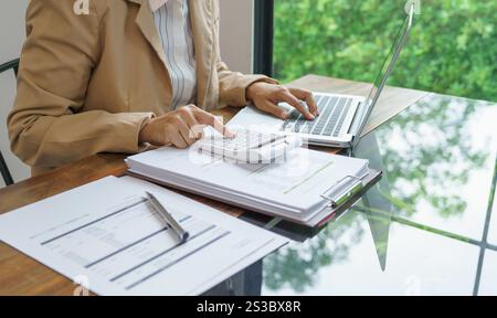 Femme d'affaires calculant l'état financier sur la calculatrice de déclaration d'impôt en ligne et de paiement Banque D'Images