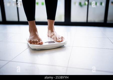 Perdez du poids. Régime gras et pieds de balance debout sur des balances électroniques pour le contrôle du poids. Instrument de mesure en kilogramme pour régime alimentaire. Banque D'Images