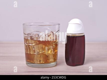 Boire avec des glaçons à côté de la bouteille de concentré de sirop. Banque D'Images