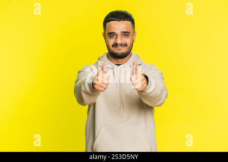 J'aime. L'homme indien soulève les pouces vers le haut est d'accord avec quelque chose ou donne une réponse positive recommande la publicité aime la rétroaction de bonne idée, célébrant la victoire de succès. Guy isolé sur fond jaune studio Banque D'Images