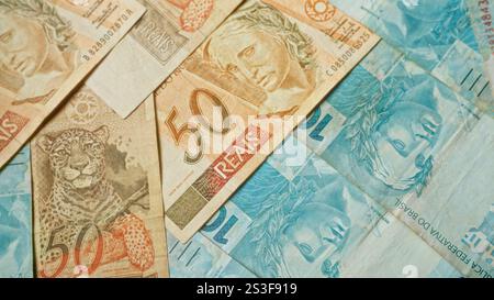 Gros plan détaillé des billets de banque réels brésiliens présentant différentes valeurs, dont 2 et 50 reais, mettant en évidence des motifs complexes et des couleurs dif Banque D'Images