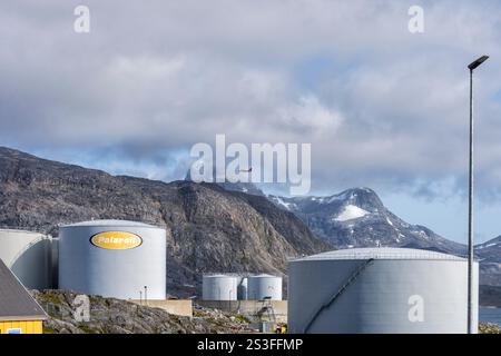 Un avion d'Air Greenland survole un terminal pétrolier avec de grands réservoirs de carburant. Montagnes en arrière-plan. Nuuk, ouest du Groenland, Danemark Banque D'Images