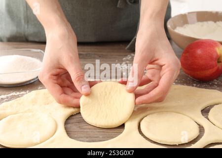 Femme faisant des pirozhki (tartes à pâtisserie farcies) à la table en bois, gros plan Banque D'Images