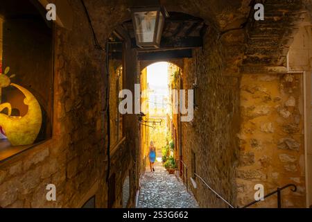 Une jeune femme descend les escaliers dans un passage couvert en tunnel dans la ville médiévale perchée de Saint-Paul de Vence, en France. Banque D'Images