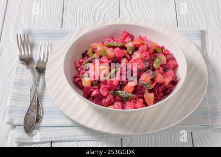 Rosolli, salade de Noël traditionnelle finlandaise dans un bol blanc sur une table en bois blanc avec fourchettes, vue horizontale d'en haut Banque D'Images