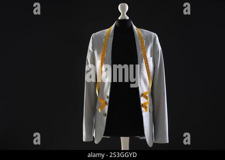 Mannequin féminin avec veste grise et ruban à mesurer sur fond sombre Banque D'Images