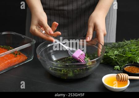 Femme faisant marinade de soja pour le filet de saumon à la table texturée gris foncé, gros plan Banque D'Images