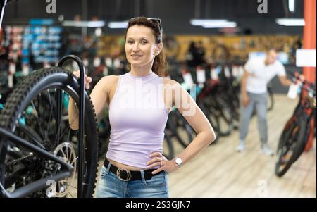 Femme souriante examinant le système de roue de vélo dans le magasin Banque D'Images