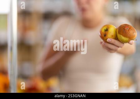 En magasin, la fille frustrée tient des fruits pourris dans les mains, gros plan Banque D'Images