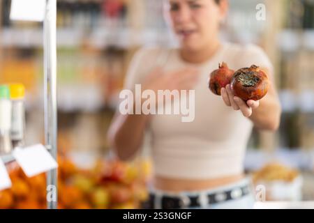 En magasin, la fille frustrée tient des fruits pourris dans les mains, gros plan Banque D'Images