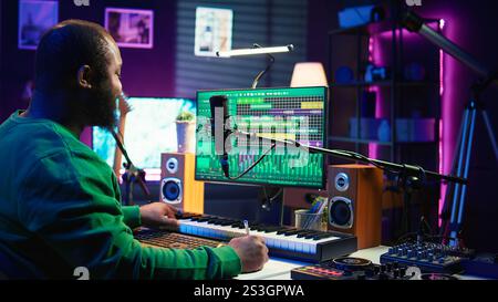 Auteur-compositeur prenant des notes pour créer de nouvelles pistes pour un album dans son home studio, écrivant des paroles et des éléments harmoniques avant d'enregistrer sa chanson et montage sur logiciel, ingénierie acoustique. Caméra B. Banque D'Images