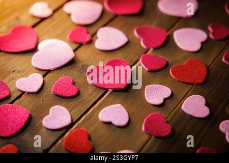 Petits coeurs découpés rouges et roses représentant la romance et l'amour. Banque D'Images