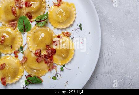 Raviolis frais, avec beurre, épices et herbes, bacon frit, sur la table, vue de dessus, fond clair, pas de gens Banque D'Images