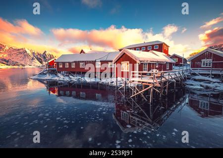 Îles Lofoten, Reine, Norvège et Hamnoy village de pêcheurs avec des maisons rouges rorbuer dans le paysage de coucher de soleil d'hiver Banque D'Images