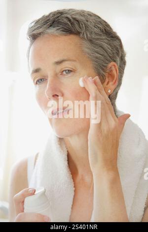 L'application de crème hydratante femme sur le visage Banque D'Images