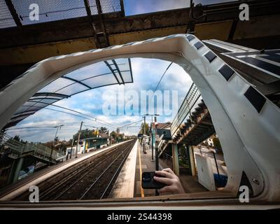 Reflet dans un miroir de gare montrant des voies vides et un ciel nuageux pendant midi Banque D'Images