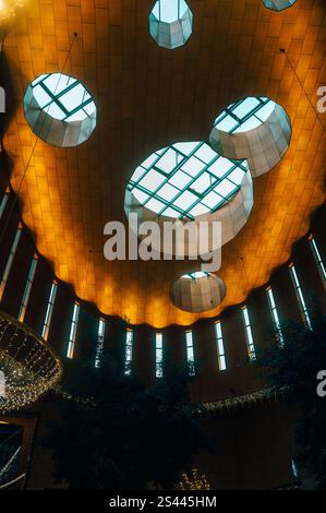Plafond moderne dans un centre commercial à Enschede avec puits de lumière circulaires et éclairage chaleureux. Un mélange architectural de lumière, de géométrie et de contemplation Banque D'Images