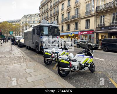 Véhicules de police garés dans une rue parisienne animée lors d'un événement public avec des magasins et des piétons dans la lumière tôt le matin Banque D'Images