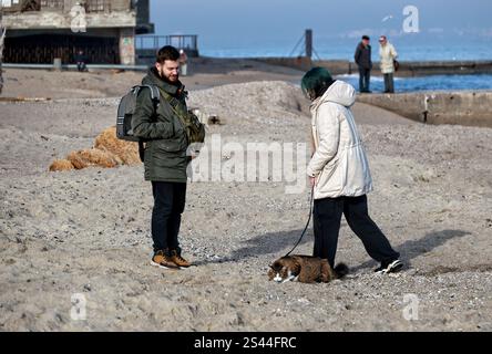 ODESSA, UKRAINE - 9 JANVIER 2025 - Un homme et une femme marchent un chat en laisse à Delfin (dauphin) Beach, Odessa, dans le sud de l'Ukraine. Banque D'Images