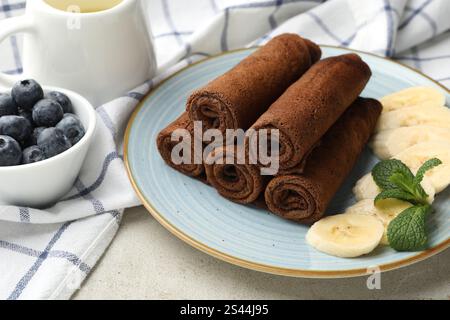 Délicieuses crêpes au chocolat à la banane et aux myrtilles servies sur une table lumineuse, en gros plan Banque D'Images
