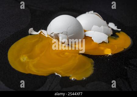 Oeuf de poule cassé avec coquille blanche et jaune sur fond noir, gros plan Banque D'Images